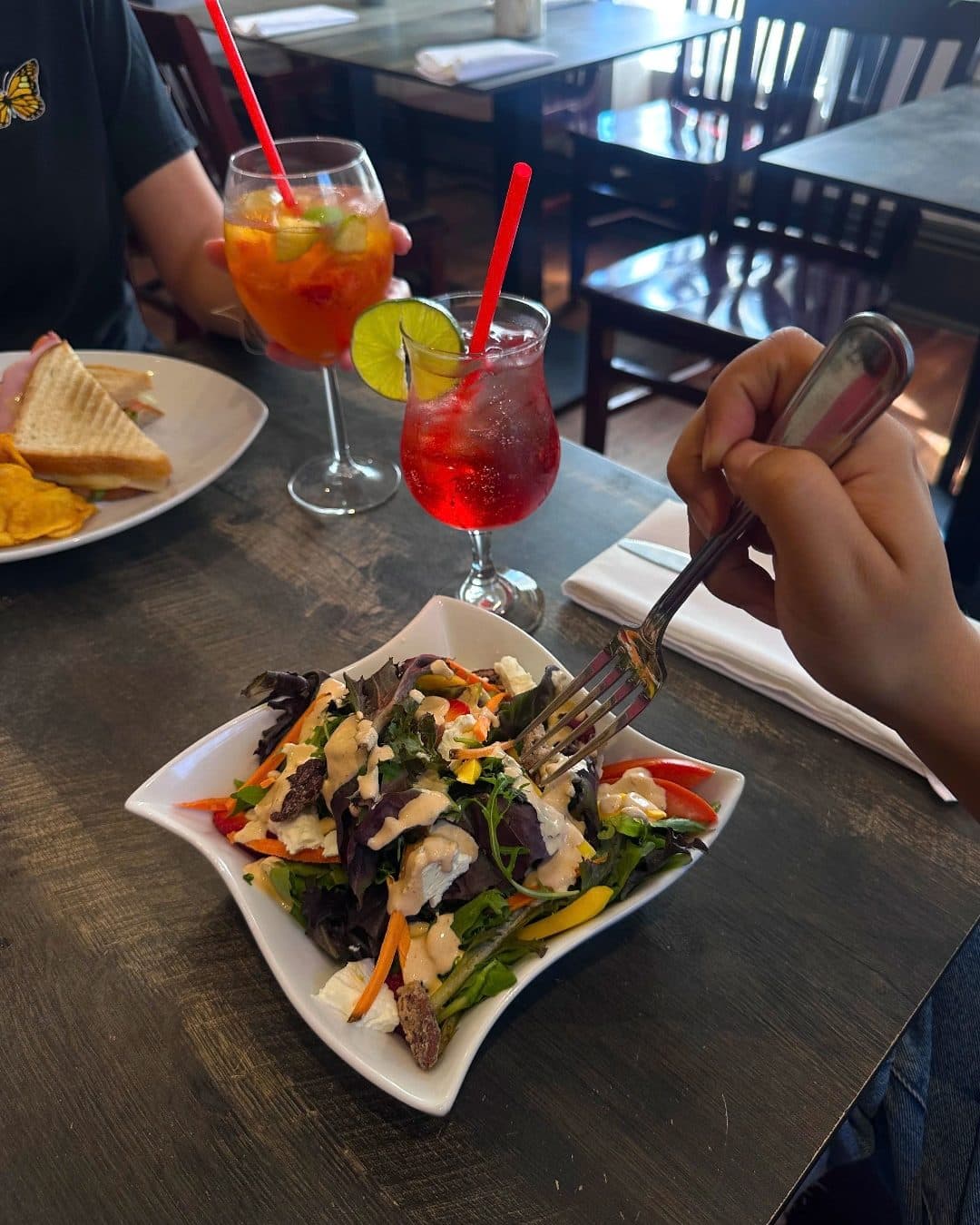 Salad and a toasted sandwich served with spritzes
